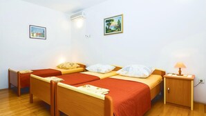A room with two single beds, a wooden nightstand, a lamp, and two framed pictures on the wall.