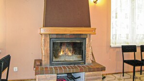 Una chimenea con revestimiento de ladrillo y repisa de madera, frente a una pared de color melocotón.