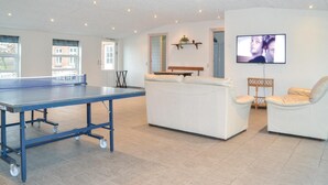 A spacious living area with a ping pong table, a white sofa, a bench, and a TV mounted on the wall. - Lovely home in Grindsted with house a panoramic view (Grindsted)