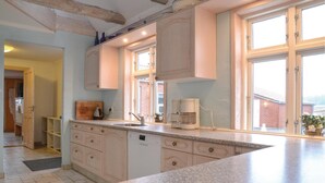 A kitchen with a granite countertop, wooden cabinets, a coffee maker, and a view of the outside through large windows. - Lovely home in Grindsted with house a panoramic view (Grindsted)