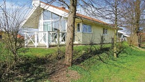 Une maison à deux étages, avec une façade blanche, un toit recouvert de tuiles rouges et un porche blanc.