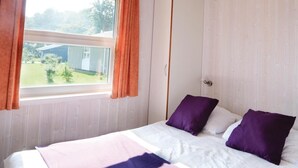 Une chambre à coucher avec un lit, une armoire et une fenêtre avec des rideaux.
