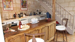 A rustic kitchen with a wooden bar, bar stools, and a staircase. - 2 bedroom beautiful home in Bellegarde (Bellegarde)