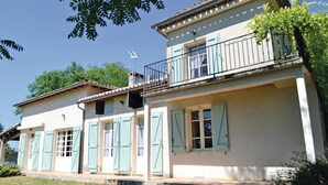 A two-story house with a balcony, shutters, and a chimney.