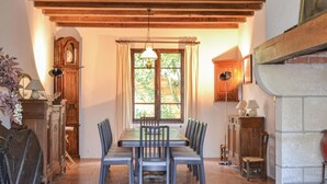 A dining area with a wooden table and chairs, a clock, and a window with curtains.