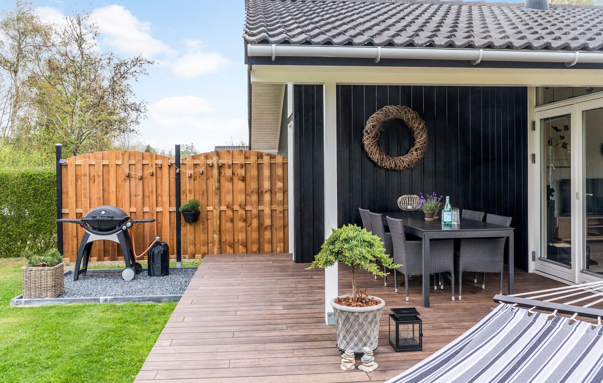 A patio with a grill, outdoor furniture, and a potted plant.