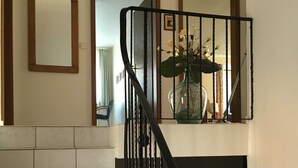 Eine Treppe mit weißen Fliesen führt zu einem Zwischenpodest mit einem schwarzen Geländer.