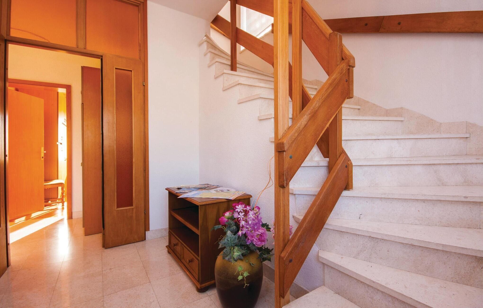 A wooden staircase with a vase of flowers on the landing.