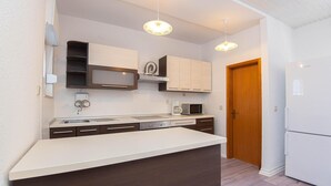 Een moderne keuken met witte kasten, een ingebouwde magnetron, een koffiezetapparaat en een houten deur.