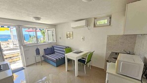 A compact kitchen with a dining area, a sofa, and a view of the sea through a window. - Holiday apartment with 24 square meter terrace (Novi Vinodolski)