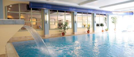 Una piscina techada, sillones reclinables de piscina