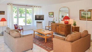 A living room with a sofa set, a coffee table, a TV, a cabinet, and a large window with curtains.