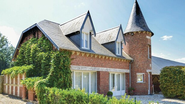 A traditional brick building with a prominent tower and steeply pitched roof.