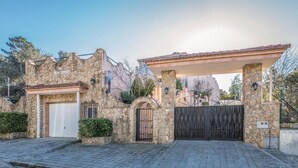 Un edificio de piedra con entrada porticada, una puerta de garaje blanca y un camino de entrada cubierto.