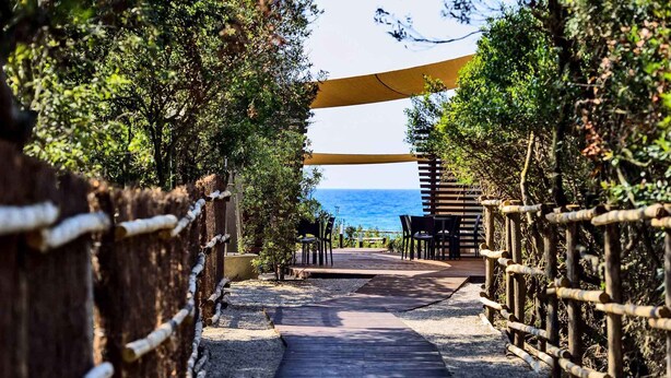 A pathway leading to a seating area with a view of the sea. - Bungalow in the Rocchette Holiday Resort (Castiglione della Pescaia)