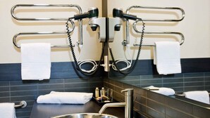 A modern bathroom with a large mirror, two towel racks, a stainless steel sink, and a small tray with toiletries. - Bungalow in the Rocchette Holiday Resort (Castiglione della Pescaia)