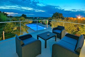 Una terraza en la azotea con piscina, muebles de mimbre y vistas al paisaje.