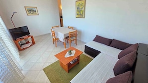 Een woonkamer met een bank, salontafel, tv-meubel en een eethoek met stoelen en een tafel.