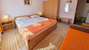 Een hotelkamer met een groot bed, een houten garderobe, nachtkastjes en een bankje.