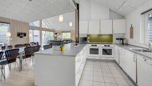 Una cocina moderna con armarios blancos, una isla grande y un comedor con sillas y una mesa.