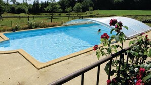 Ein Pool mit geschwungener Kante, umgeben von einer Betonplattform und einem Metallgeländer.