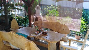 A rustic wooden table with a unique curved backrest, surrounded by potted plants and a small statue. - Holiday apartment with terrace, Wi-Fi and air conditioning (Hévíz)