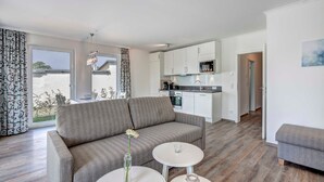 A modern living room with a sofa, a dining table, and a kitchen in the background. - Villa Margarete Whg. 6 - Villa Margarete, BEACH NEXT (Heringsdorf)