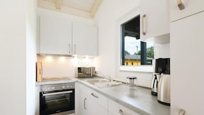 A compact kitchen with white cabinets, a built-in oven, a coffee maker, and a window providing a view of the outside. - Amazing home in Thale with sauna (Thale)