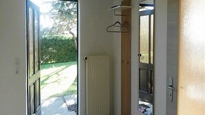 Una porta aperta che dà su un corridoio con termosifone, appendiabiti e vista su un giardino.