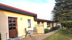 Un edificio con una facciata gialla, una porta marrone e un piccolo patio con tavolo e sedie.