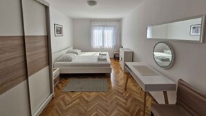 Une chambre à coucher moderne avec un lit, une table de chevet, un miroir et un parquet à motifs en chevrons.