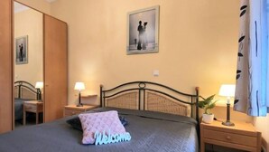 A bedroom with a bed, bedside tables, a nightstand, a mirror, and a framed picture on the wall. - (109) 2-room apartment - apartment house Dünenschloss (Kühlungsborn)