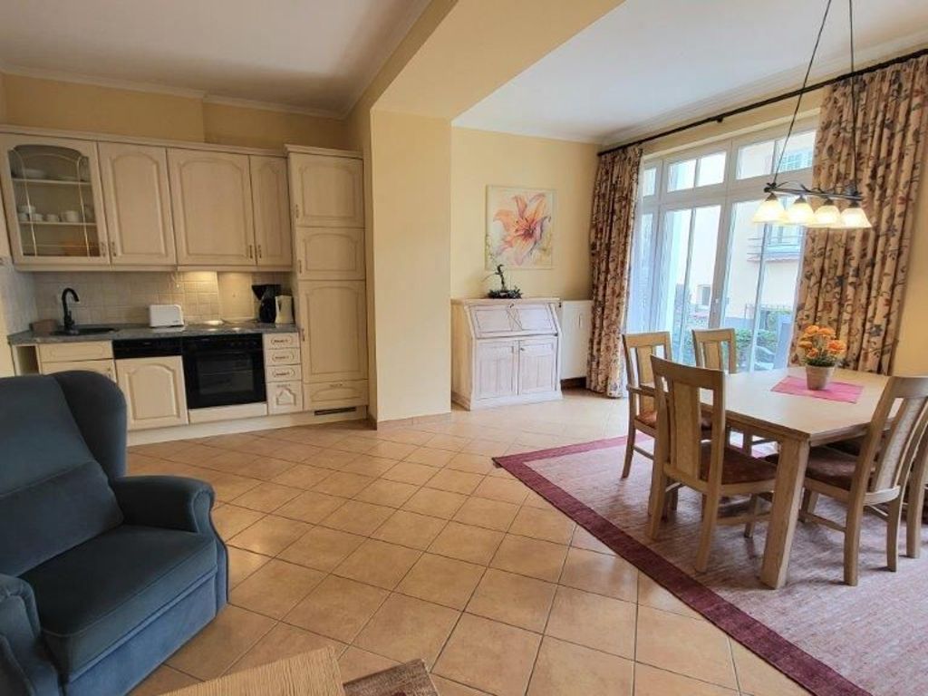 A spacious living area with a dining table, a sofa, and a kitchen area with cabinets and a stove.