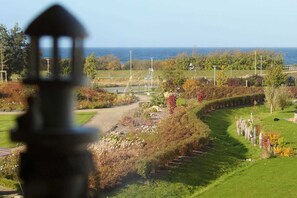 A landscaped garden with a pathway, a body of water, and a distant view of the ocean. - Beach Apartment with Fireplace · Balcony · 300 m from the Beach - Accommodation (Börgerende-Rethwisch)