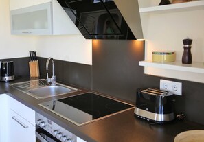 A modern kitchen with a stainless steel sink, a built-in stovetop, and a toaster. - Beach Apartment with Fireplace · Balcony · 300 m from the Beach - Accommodation (Börgerende-Rethwisch)