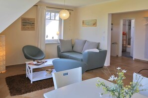 A modern living room with a sofa, a chair, a table, and a window with curtains.