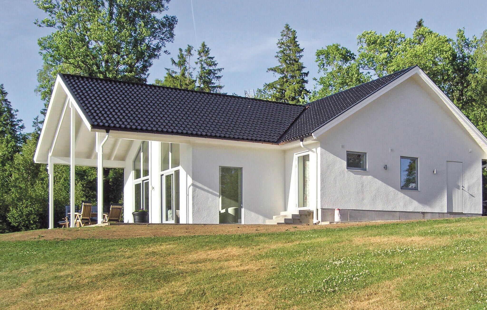 Ein modernes, zweistöckiges Haus mit Satteldach, großen Fenstern und einer überdachten Veranda.