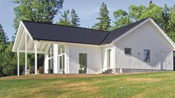 Ein modernes, zweistöckiges Haus mit Satteldach, großen Fenstern und einer überdachten Veranda.