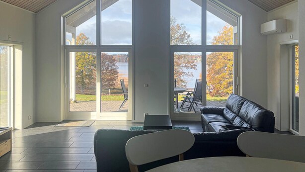 Una habitación amplia con ventanas grandes, un sofá de cuero negro y una mesa de comedor.