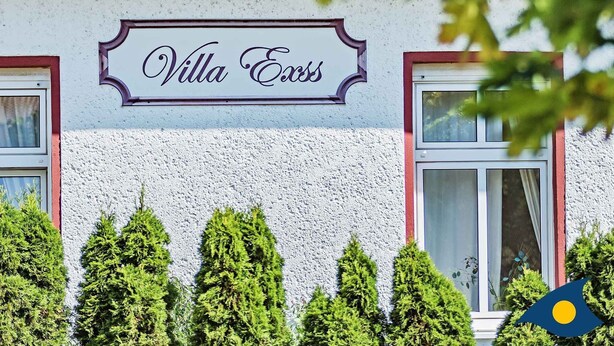 A building with a sign reading "Villa Exis" and a window with a curtain. - Villa Exss Whg. 01 /- - VE 01 (Heringsdorf)
