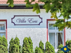 Un bâtiment sur lequel on peut lire l’inscription « Villa Exis », et une fenêtre avec un rideau.