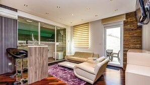 Ein modernes Wohnzimmer mit einer Couch, einem Couchtisch und einem Essbereich mit Glastrennwand.