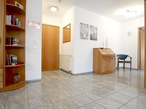 A hallway with a wooden bookshelf, a wooden cabinet, and a chair.