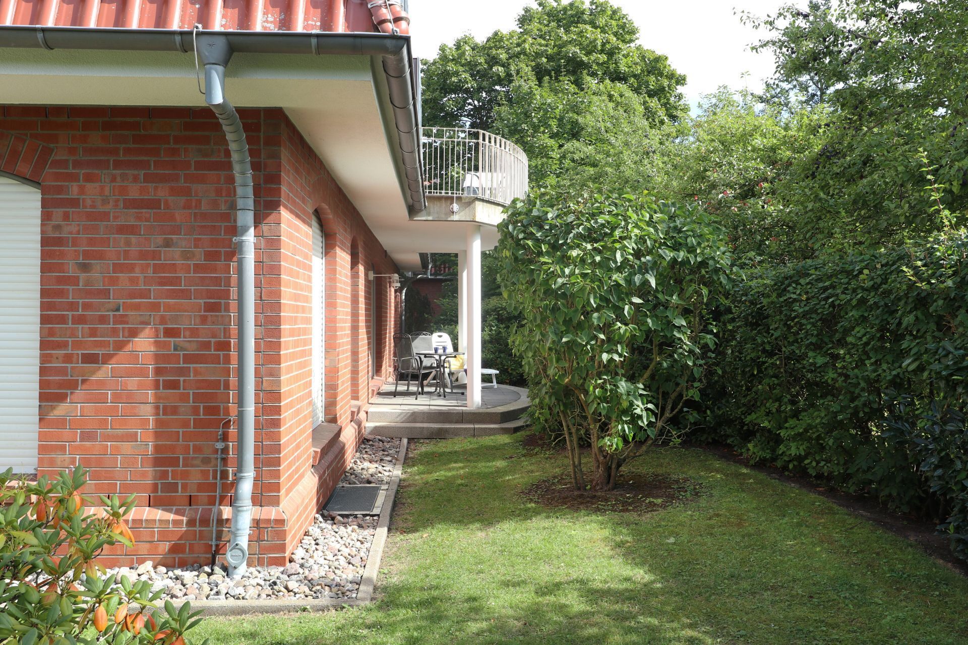 Ein Backsteinhaus mit überdachter Terrasse und kleinem Garten.