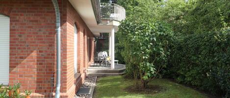 Ein Backsteinhaus mit überdachter Terrasse und kleinem Garten.