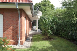Et murstenshus med en overdækket terrasse og en lille have.