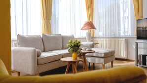Un salon moderne avec un canapé, une table basse, une lampe et un téléviseur.