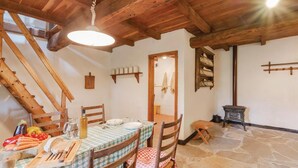 A rustic dining area with a wooden table set for two, a wooden chair, a stone floor, and a wooden staircase. - Awesome home in Borgo Val di Taro PR with WiFi (Borgo Val di Taro PR)