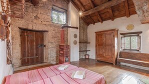 A rustic room with a wooden bed, a large cabinet, and a stone wall. - Awesome home in Borgo Val di Taro PR with WiFi (Borgo Val di Taro PR)