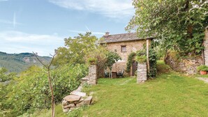 A stone house with a stone staircase leading to a wooden door, surrounded by lush greenery and a clear sky. - Awesome home in Borgo Val di Taro PR with WiFi (Borgo Val di Taro PR)